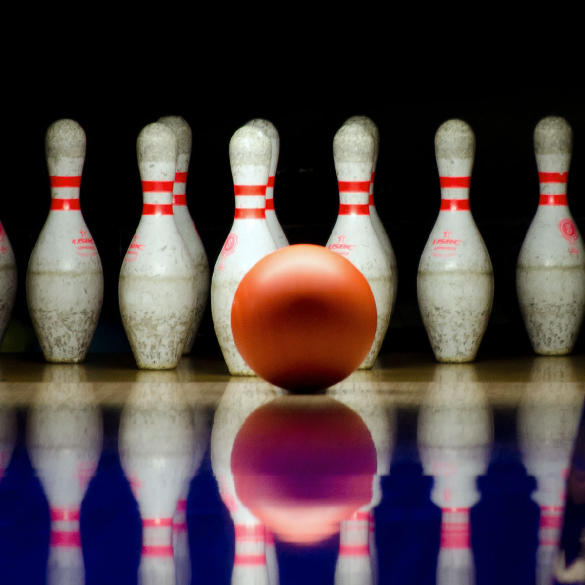 Bowlingkegel stehen in einer Reihe vor einem schwarzen Hintergrund.