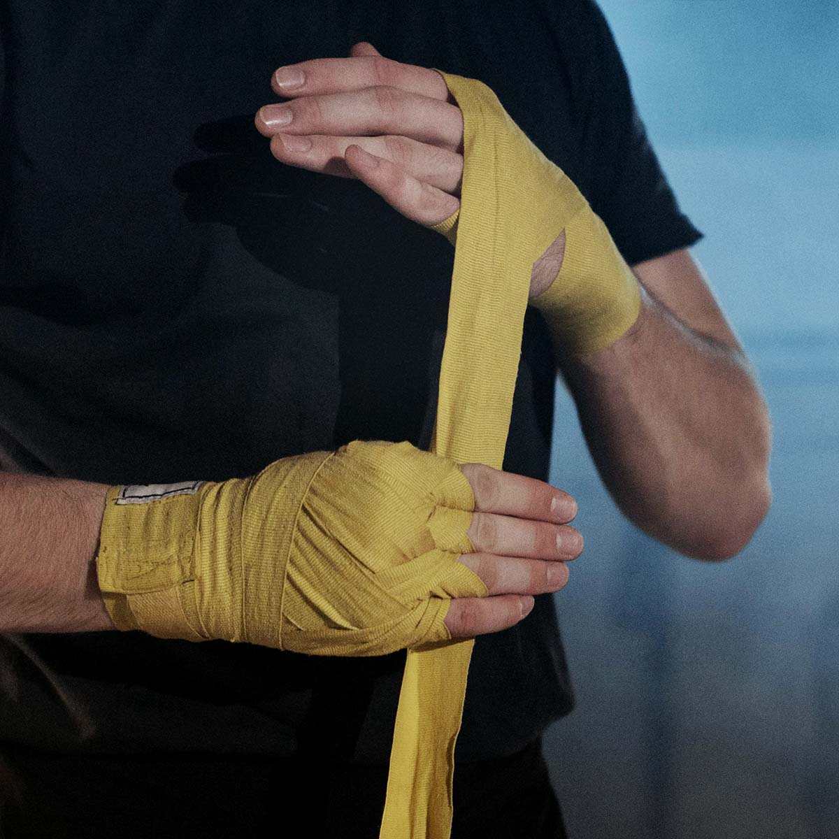Mann mit gelben Bandagen an den Händen, der sich auf das Kickboxen vorbereitet.