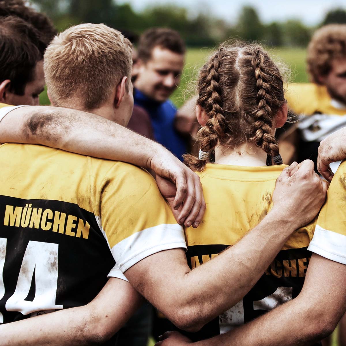 Rugbyspieler in gelben und schwarzen Trikots, die als Team auf dem Feld stehen.