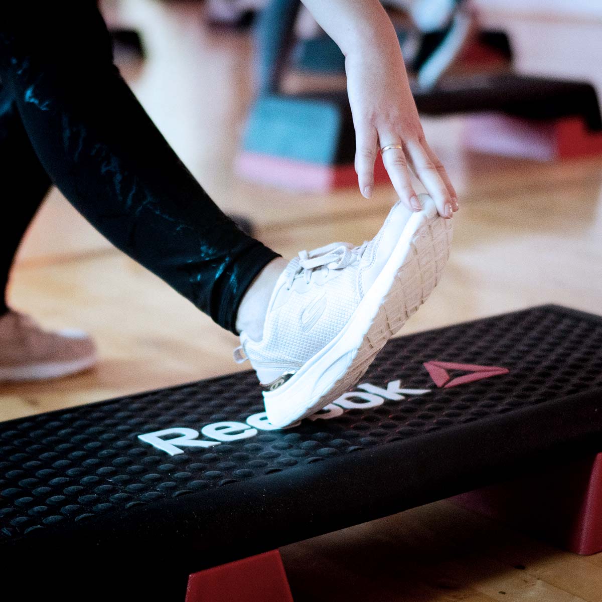 Eine Person übt Step-Aerobic auf einem schwarz-weißen Step.