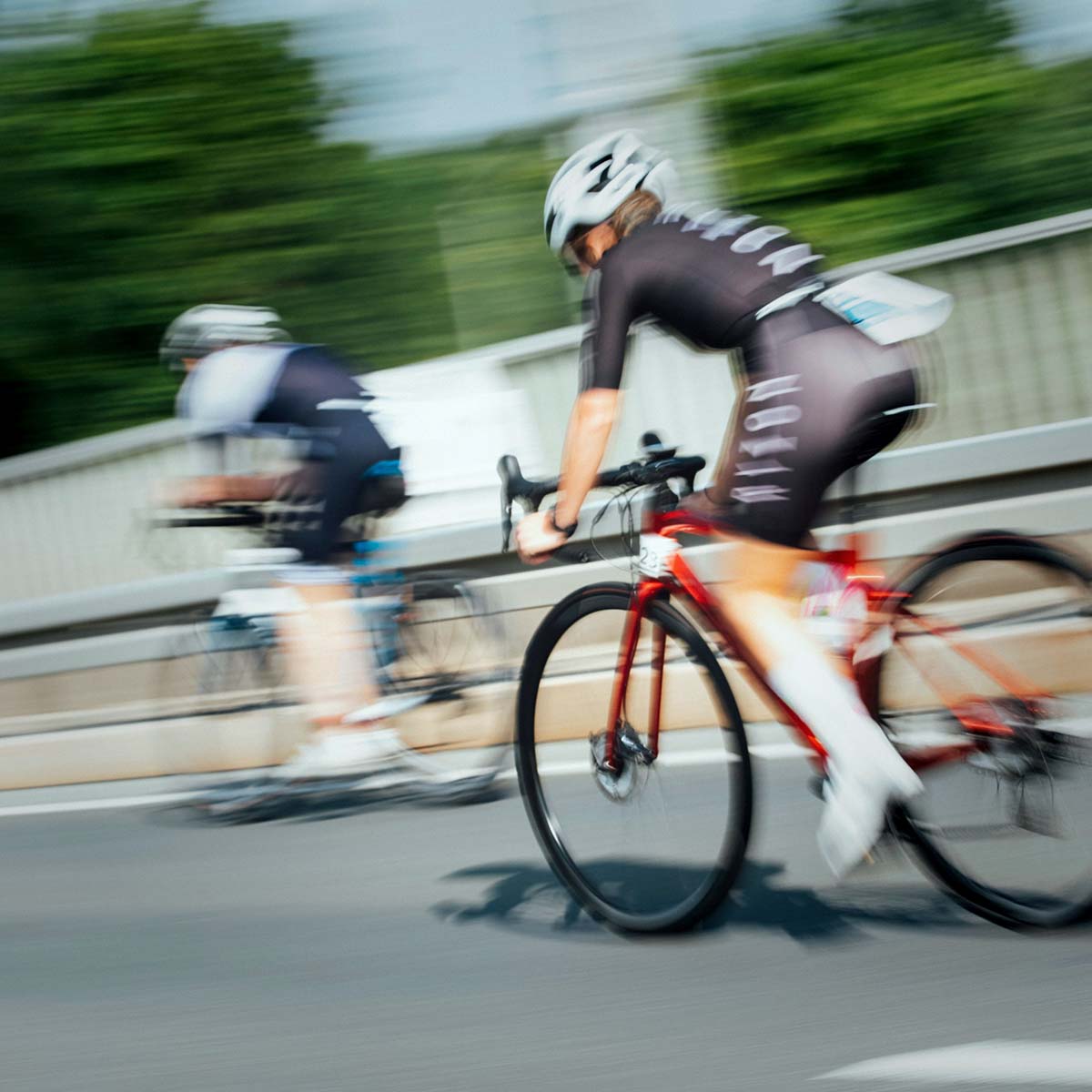 Zwei Personen radeln auf einer Straße während eines Triathlon-Wettkampfs.