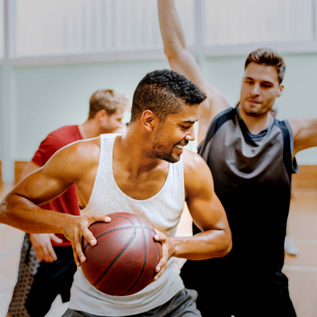 Eine Gruppe von Männern spielt Basketball in einer Sporthalle.