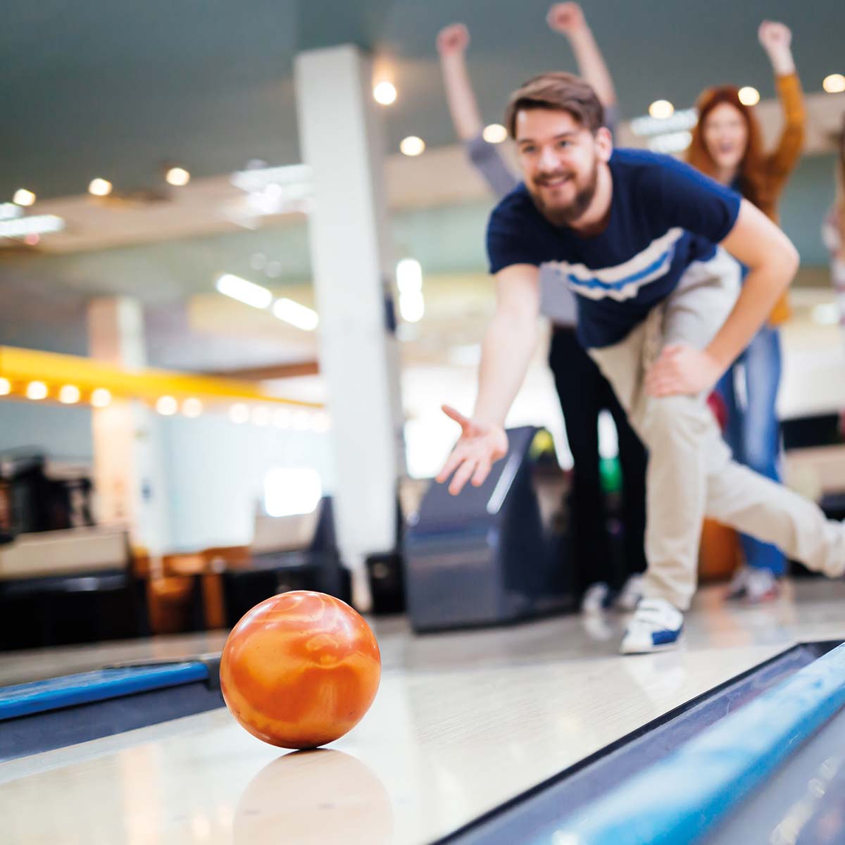 Ein Mann und eine Frau spielen Bowling und werfen gemeinsam eine Bowlingkugel.