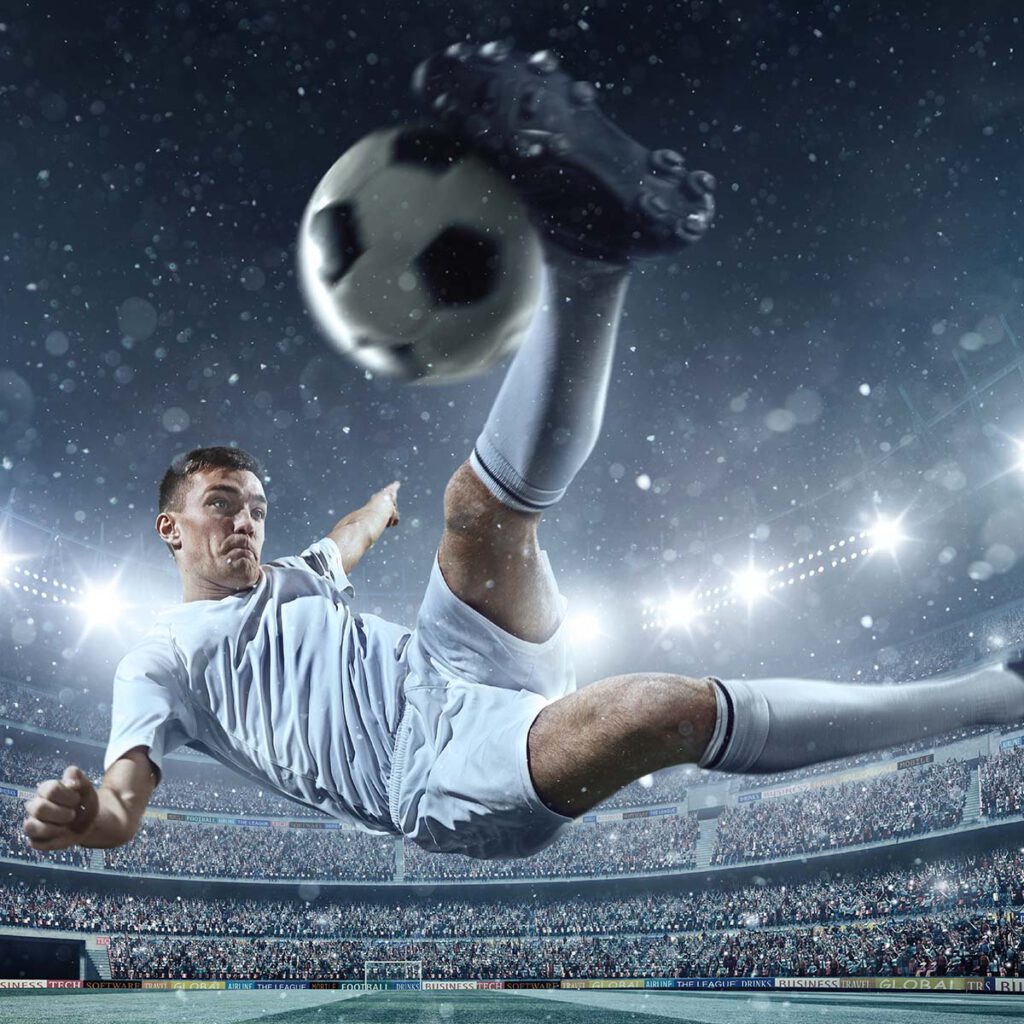 A footballer kicks the ball into the air.