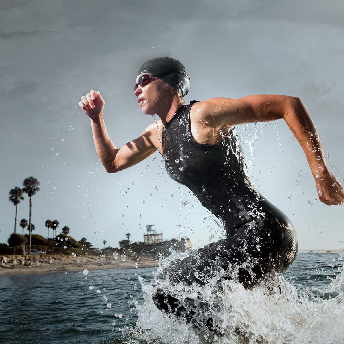 Eine Frau im Neoprenanzug läuft durch das Wasser des Ozeans.